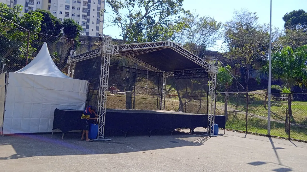 Palco com cobertura de treliça montado ao lado de uma tenda chapéu de bruxa