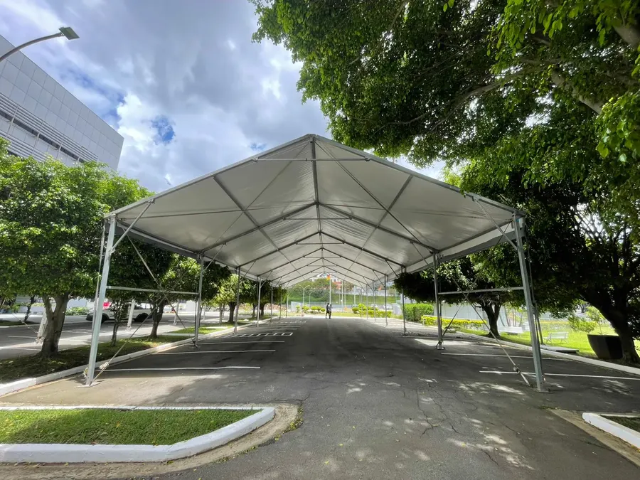 Tenda galpão 2 águas com a estrutura aberta, montada sobre a via de um estacionamento